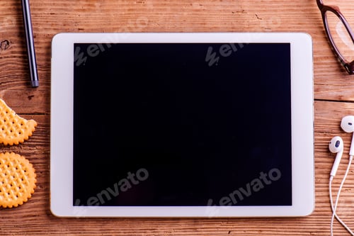 Preview: Tablet, earphones, eyeglasses laid on office desk, studio shot