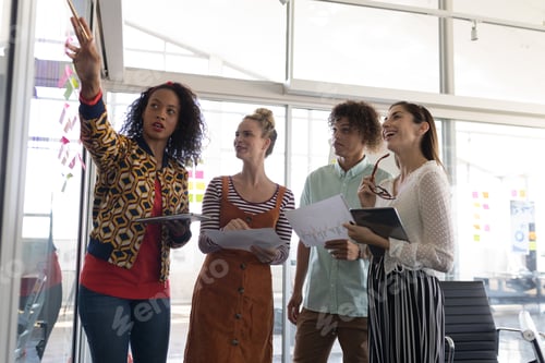 Preview: Diverse business colleagues discussing plans over sticky notes in modern office