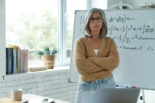 Preview: Senior woman standing near the whiteboard at classroom