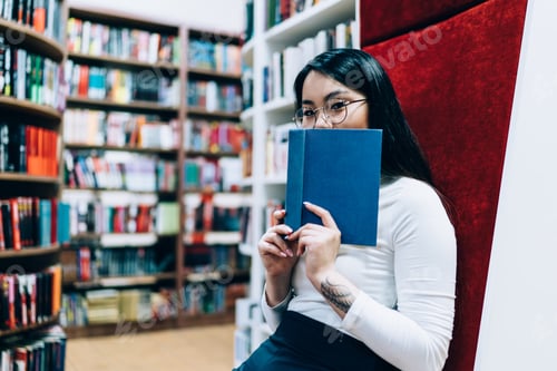 Preview: Young attractive female in glasses sitting with book