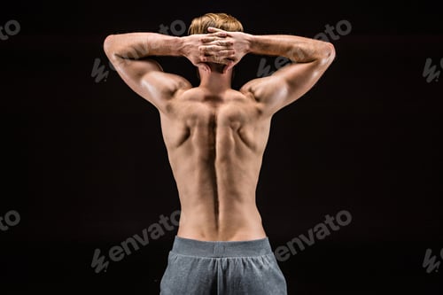 Preview: back view of shirtless bearded bodybuilder posing isolated on black in studio