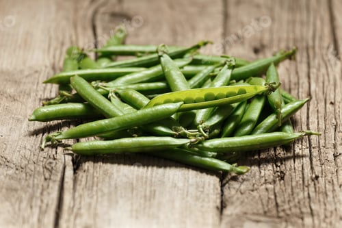 Preview: Fresh green peas in closed and open pods on a wooden background.