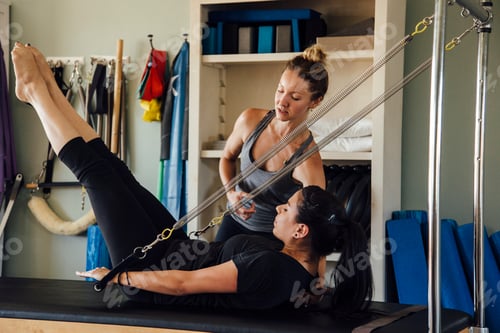Preview: Woman and personal trainer using pilates reformer