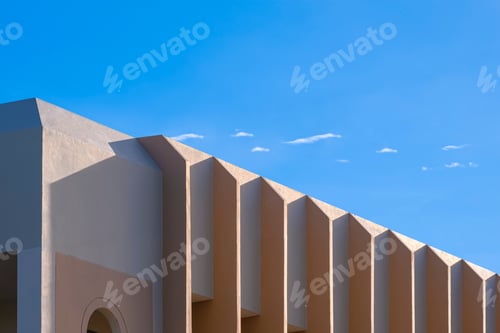 Preview: Side view of concrete wall fins sunshade on modern beige house against blue sky background