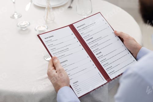 Preview: Man with menu at table in restaurant, closeup