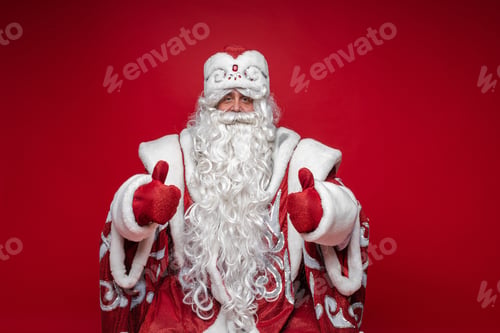 Preview: Cheerful white-bearded Santa showing thumbs up.