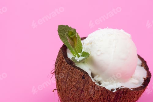 Preview: Vanilla ice cream balls in fresh coconut halves, decorated with mint leaves on a pink background