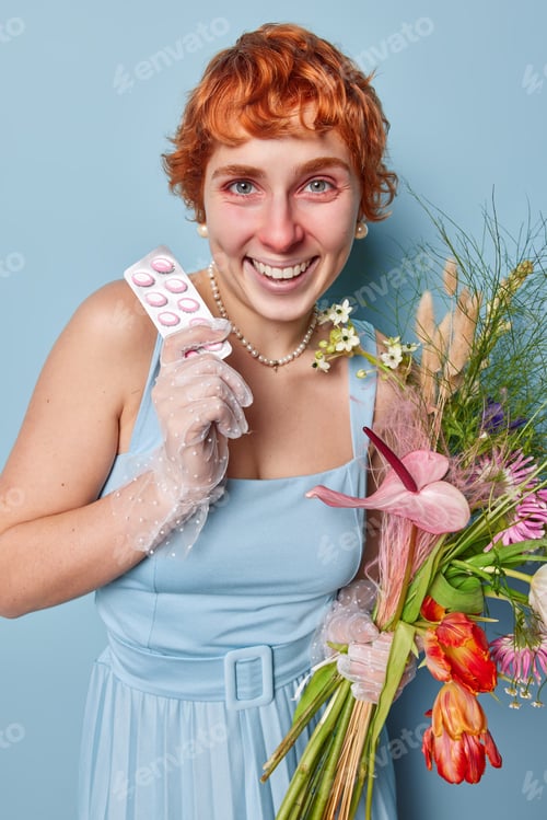Preview: Photo of cheerful redhead European woman smiles positively poses with pills and bouquet of wild