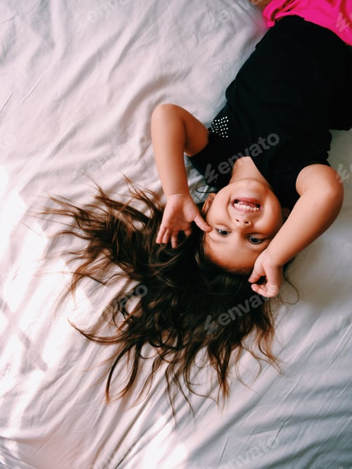 Preview: Happy Child Lying Upside Down on Bed