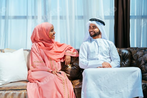 Preview: Happy middle eastern couple wearing traditional arab clothing at home