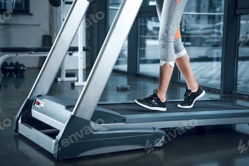 Preview: cropped shot of sportswoman running on treadmill at gym