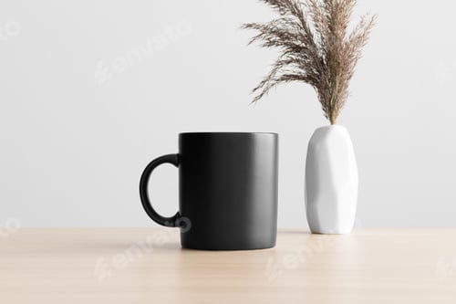 Preview: Black mug mockup with a dry flower decoration on the wooden table.