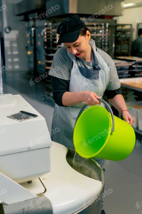 Preview: of pouring water from a green bucket into a machine with flour and yeast
