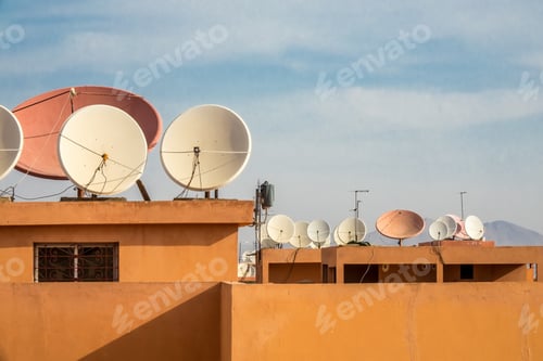 Preview: Wide angle shot of white satellite dishes on the roof of a building