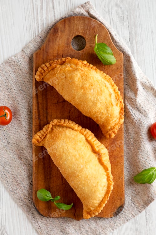 Preview: Homemade Deep Fried Italian Panzerotti Calzone on a rustic wooden board on a white wooden background