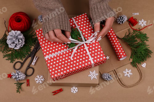 Preview: Woman packing Christmas gifts with red paper