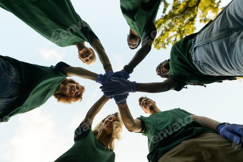 Preview: Group of volunteers joining hands wearing green t shirts