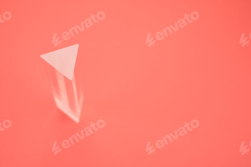 Preview: Closeup shot of a triangular glass prism isolated on a red background