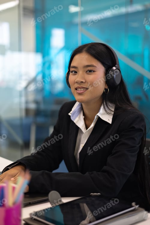 Preview: In the office, a smiling young asian businesswoman is seen working on her laptop