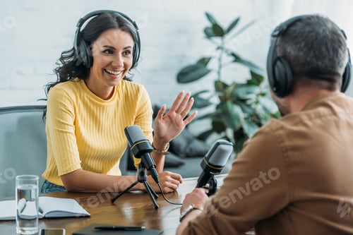 Vista previa: smiling radio host gesturing while talking to colleague in broadcasting studio