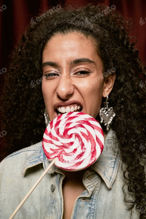 Preview: Portrait of Young Adult Middle Eastern Woman Biting Lollipop in Photo Booth