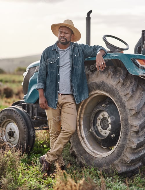 Visualização: Shot of a mature man standing next to his tractor on a farm