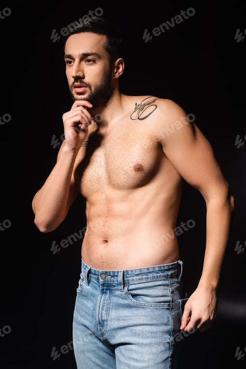 Preview: Muscular man in jeans looking away on black background