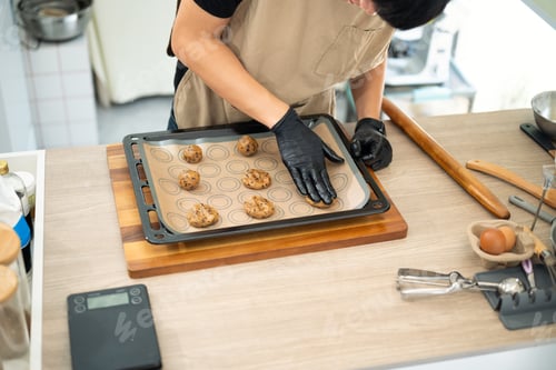 Preview: Baker preparing chocolate chip cookie dough on a baking tray