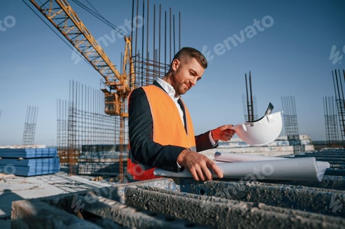 Preview: In orange colored uniform. Man is working on the construction site at daytime