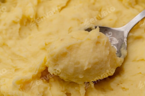 Preview: a top view close up of mashed yellow potatoes texture with spoon in it