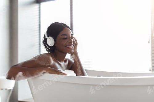 Preview: Happy african american lady taking bath and listening to music