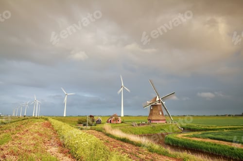 Preview: old windmill and turbines at rainy sunset