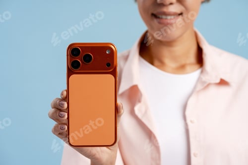 Preview: Woman holding up her smartphone, showing orange case and space for text