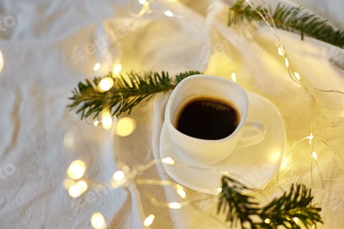 Preview: Cup of coffee in bed with a gerlands, needles and lights