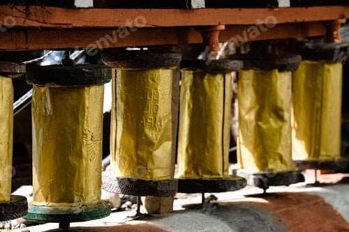 Preview: Closeup of a row of golden beautiful Tibetan prayer wheels in Nepal
