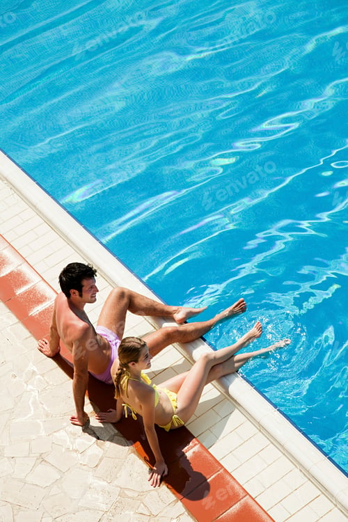 Preview: Young couple sitting at poolside