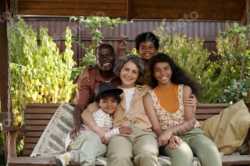 Preview: Smiling Family Sitting Together on Backyard Swing