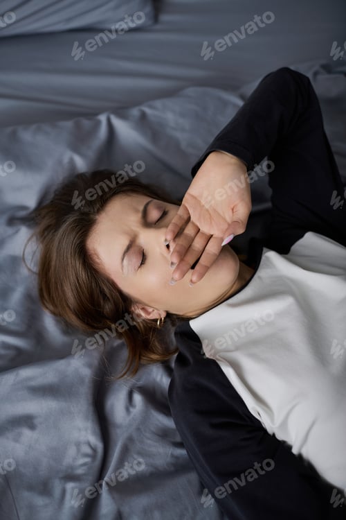 Preview: Young woman embracing a lazy day in bed surrounded by modern comforts