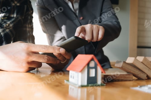 Preview: Close up of Businesswoman and customer pointing and using smartphone for buying house. Bank manager