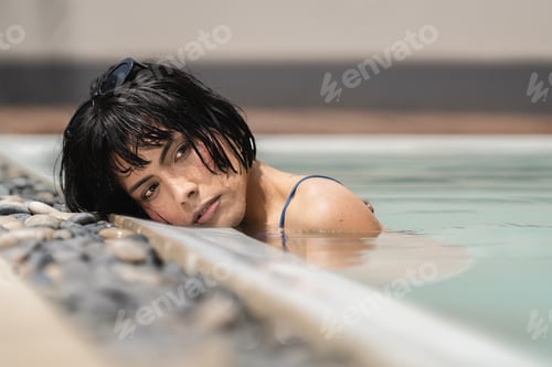 Preview: Young woman relaxing in swimming pool on summer day