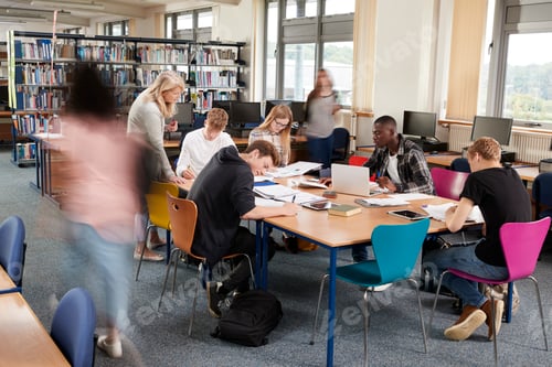 Preview: Busy College Library With Teacher Helping Students At Table