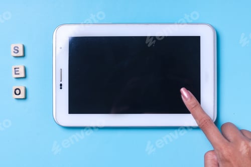 Preview: Female finger touching empty screen of tablet smartphone with SEO lettering
