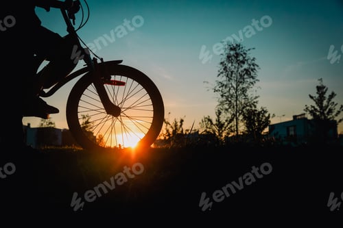 Preview: Silhouette Of Young Boy Riding Bike At Sunset