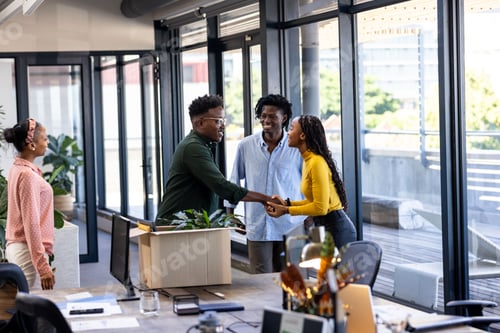 Preview: Colleagues greeting each other with handshake in modern office, smiling warmly