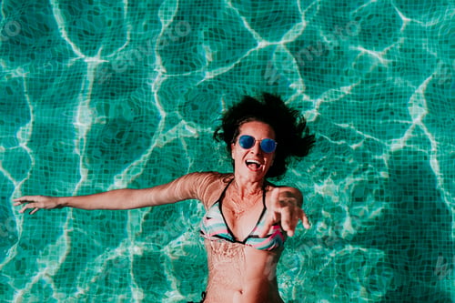 Preview: top view of happy young woman floating in a pool. summer and fun lifestyle