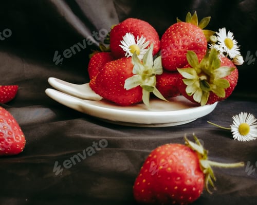 Preview: Fresh red strawberries and wild chamomile flowers on a black background