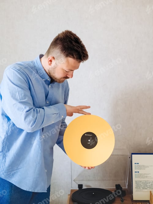 Preview: Millenial man putting yellow record on vinyl player