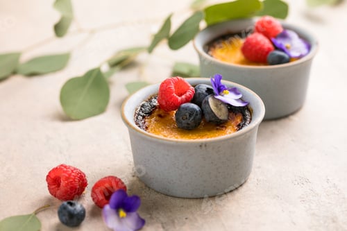 Preview: Creme brulee. French vanilla cream dessert with caramelised sugar and berries, selective focus.