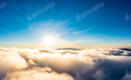 Preview: Sun shining brightly above white fluffy clouds at sunrise