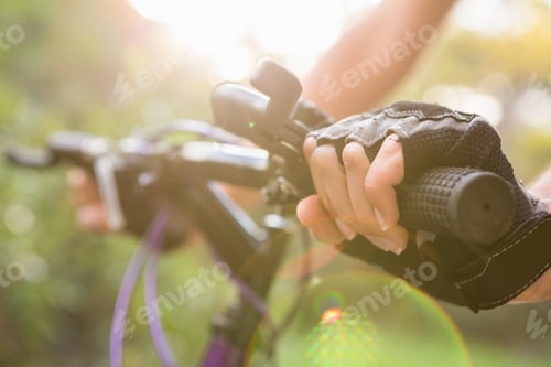 Preview: Woman mountain biking and holding handlebars in the nature